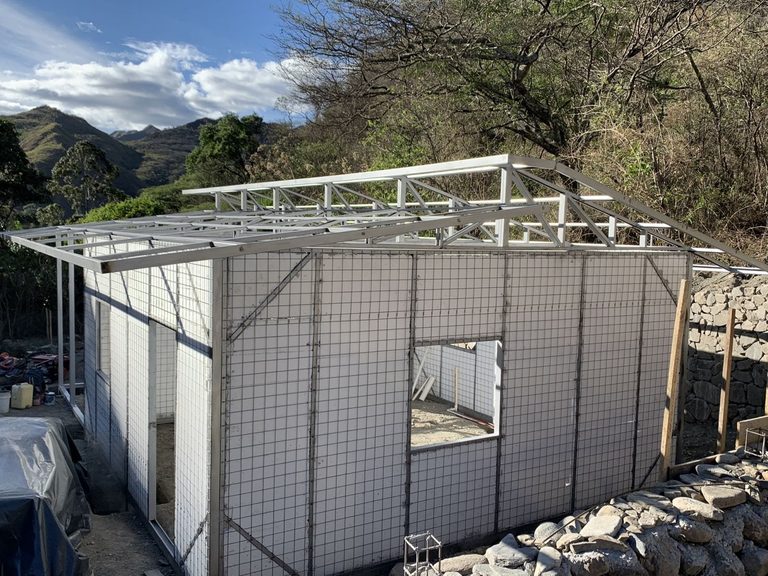 The same workshop from outside, panels and roof frame in place, with the valley behind