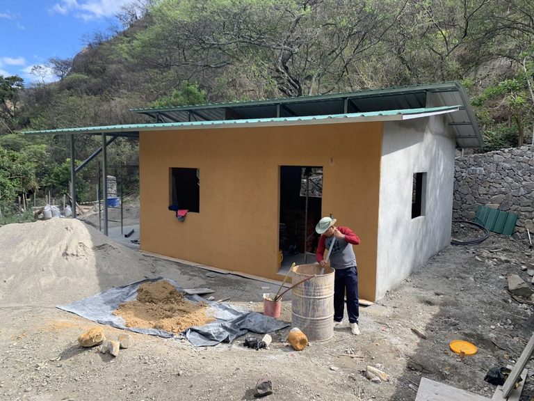The workshop finished, its walls plastered in earth, sand and cement, with a worker mixing the next batch