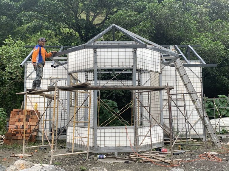 A custom art studio under construction: welded-wire wall panels in place, the steel roof frame going on, and scaffolding still standing around it